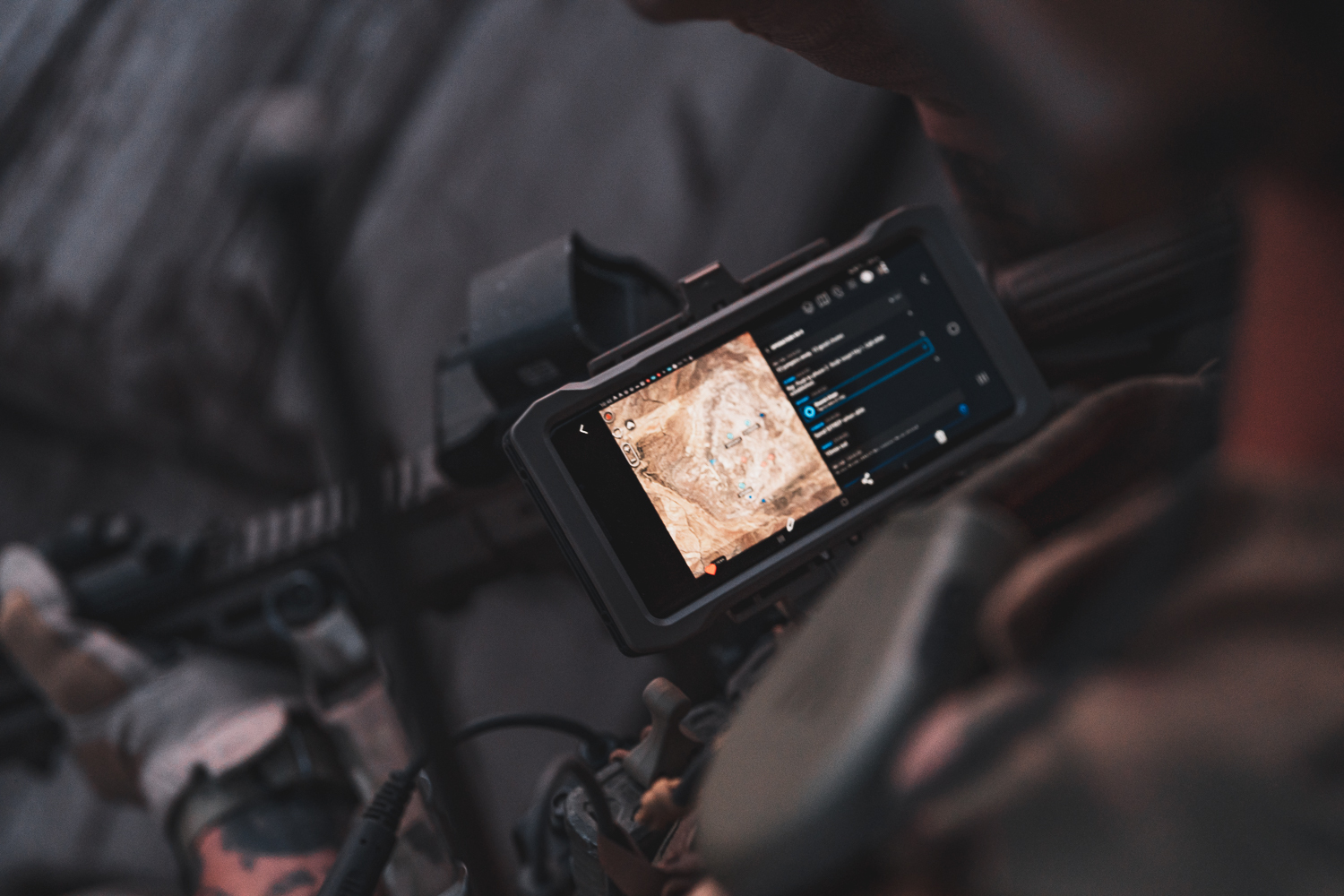 A rugged touchscreen mounted to a rifle displaying a tactical map with marked unit positions